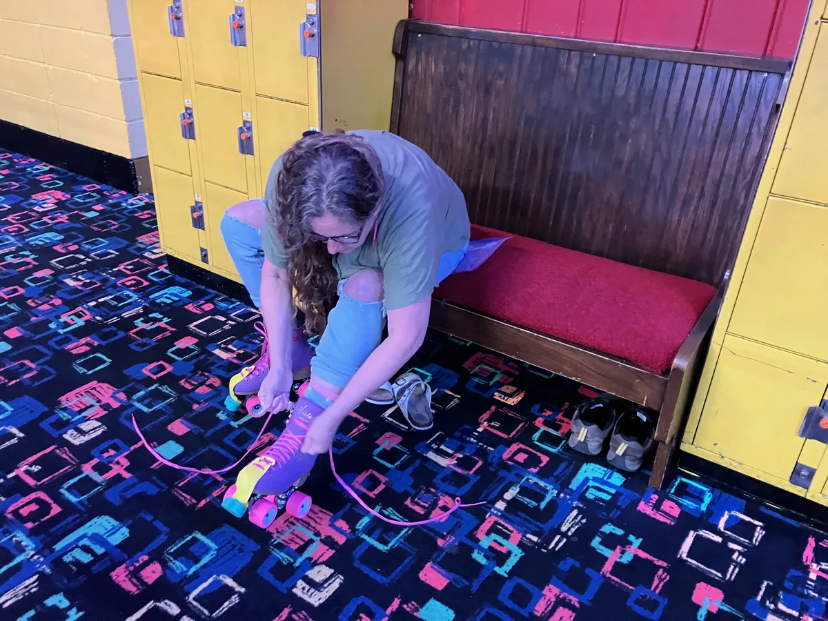 Jolynn tying her purple and pink roller skates