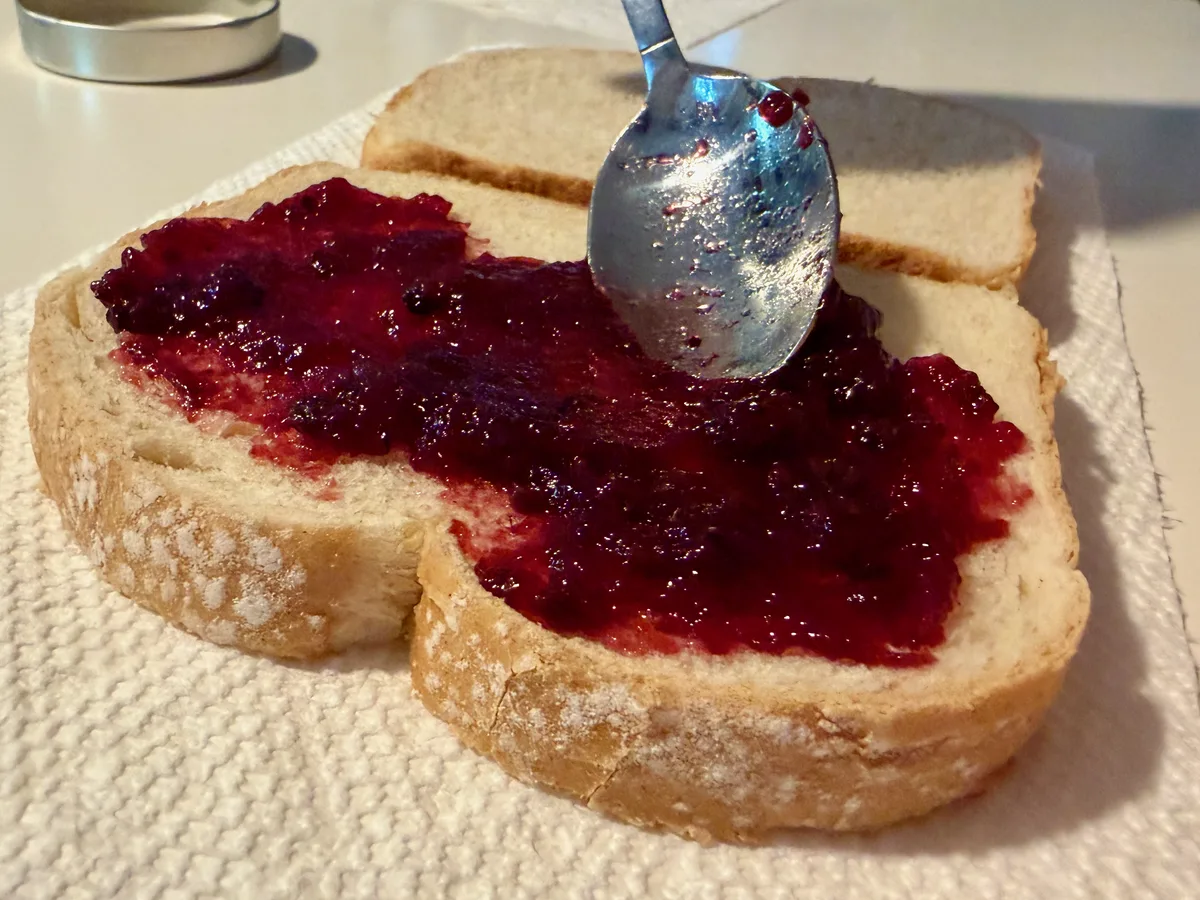 Berry jam spread almost edge to edge across a slice of bread.