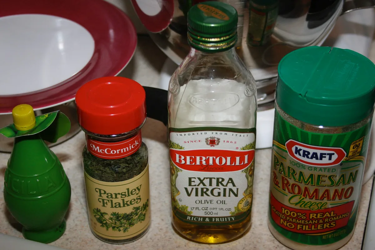 Ingredients including olive oil, parsley flakes, Parmesan cheese, and lemon juice on the counter