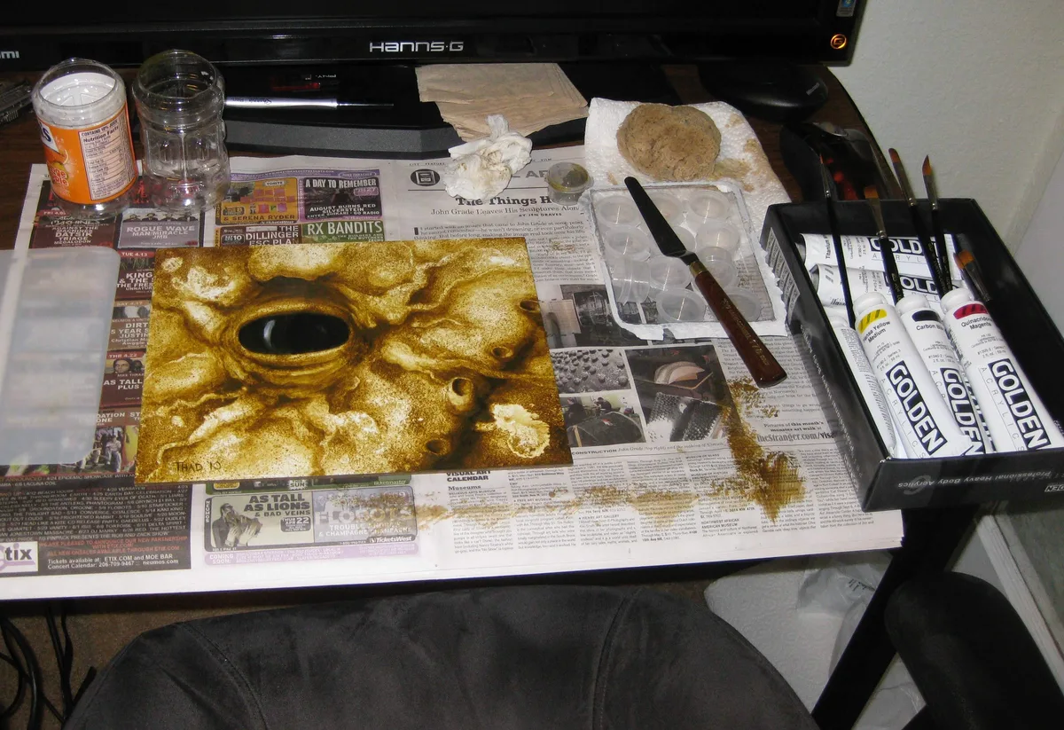 The finished Elder's Eye painting sitting on a desk covered in newspaper and paint supplies.