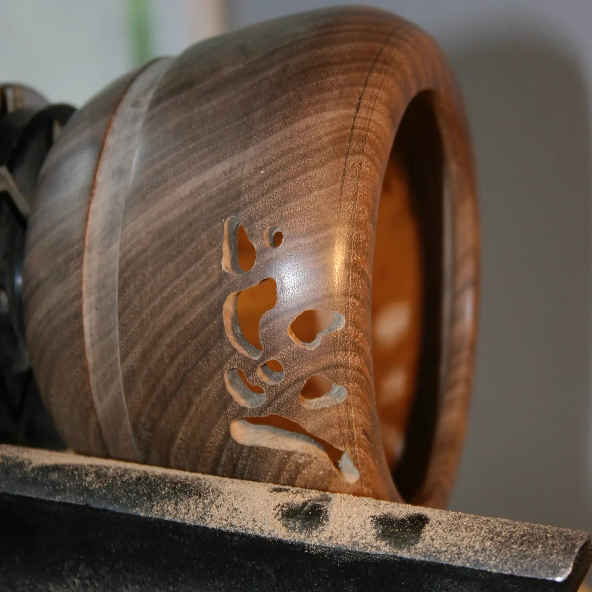 Walnut bowl on the lathe with more holes drilled into the openwork pattern