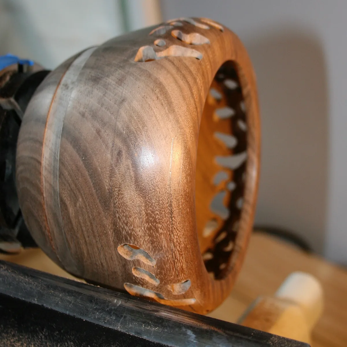 Walnut bowl on the lathe with openwork visible through the rim opening