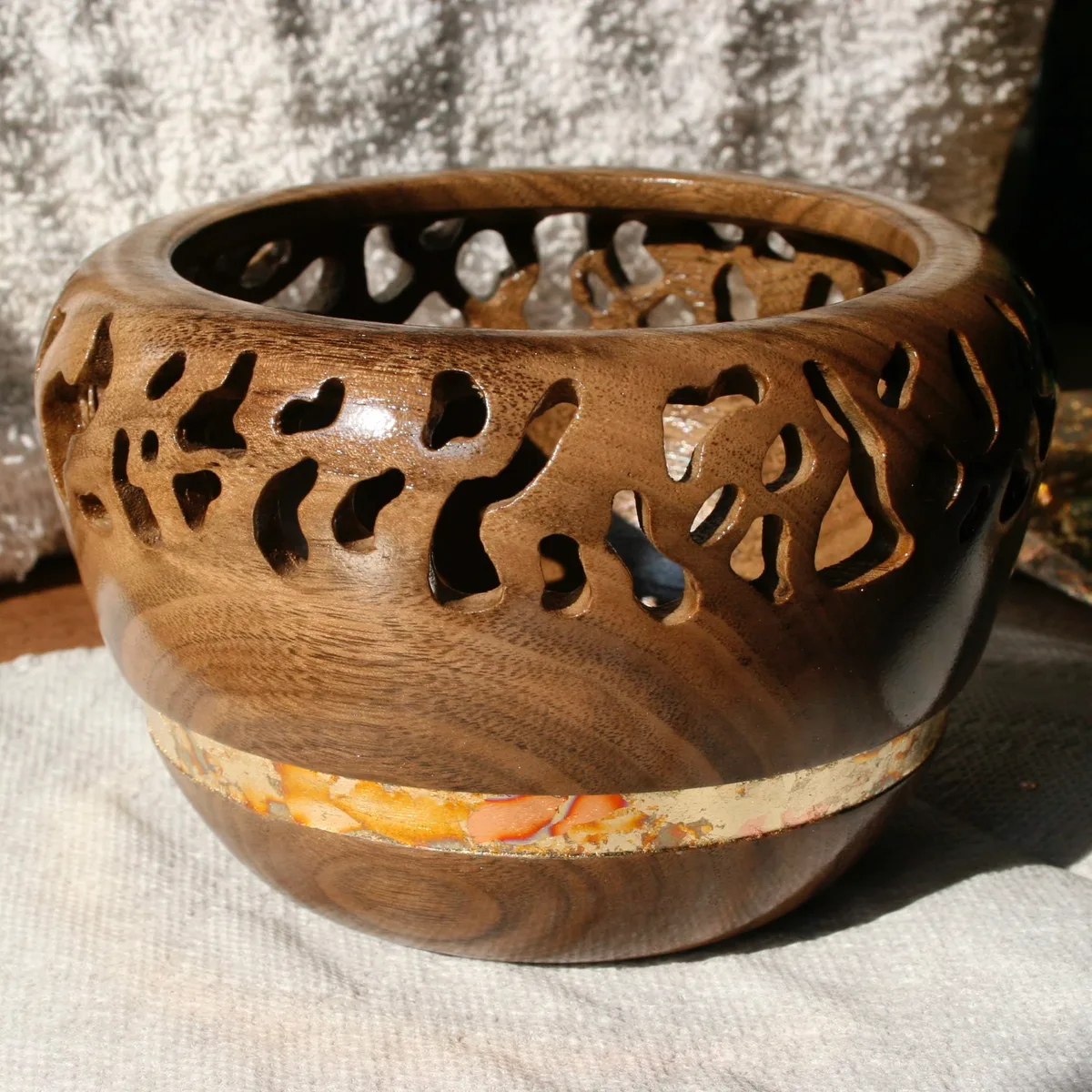 Wooden turned bowl with drilled lace-like hole pattern and a flake inlay band