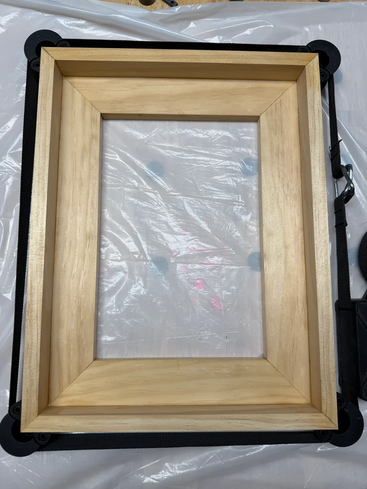 Glued corners of the wood frame held together with clamps and straps while drying.