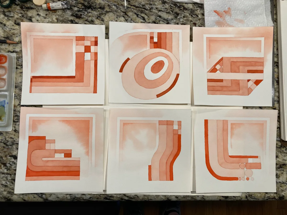 Six finished vermilion watercolor paintings arranged on a countertop